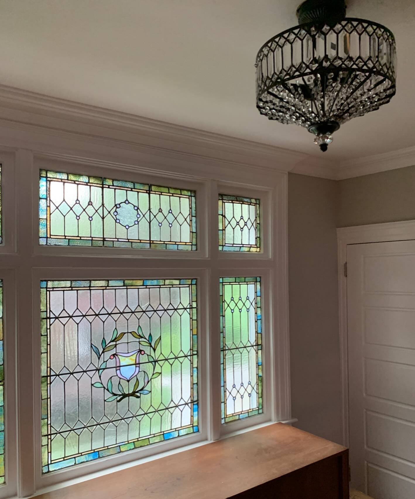 A black beaded chandelier above a wall of stained glass windows