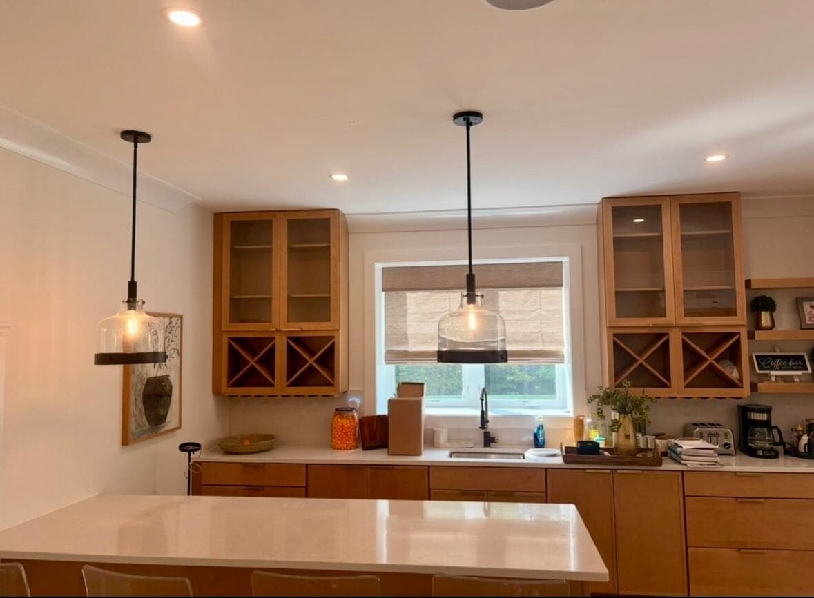 Two glass pendants over a kitchen island with recessed lights in the ceiling